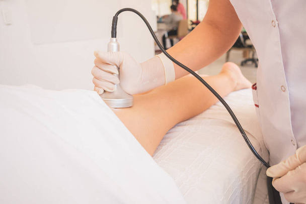 Fizjoterapeutka przeprowadzająca ultradźwiękową kawitację na kobiecie w spa. - Zdjęcie, obraz