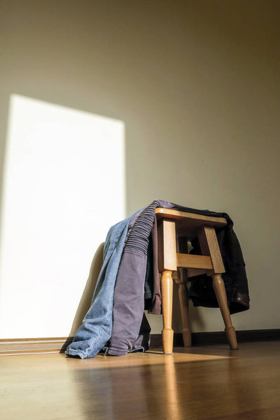 A wooden chair in the room where the clothes lie - Foto, Imagem