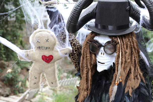 крупным планом портрет человека в страшной маске на Хэллоуин с куклой вуду - Фото, изображение