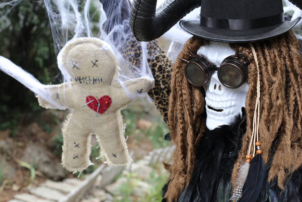 Nahaufnahme Porträt einer Person in gruseliger Halloween-Maske mit Voodoo-Puppe - Foto, Bild