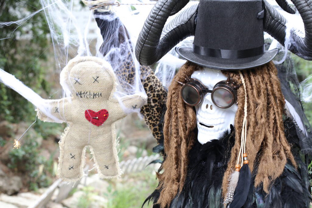 крупным планом портрет человека в страшной маске на Хэллоуин с куклой вуду - Фото, изображение