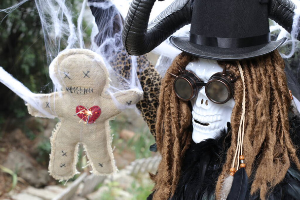 Nahaufnahme Porträt einer Person in gruseliger Halloween-Maske mit Voodoo-Puppe - Foto, Bild