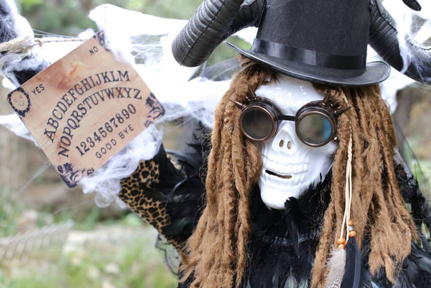 Крупный план портрета человека в страшной маске Хэллоуина, держащего спиритическую доску Уиджи - Фото, изображение