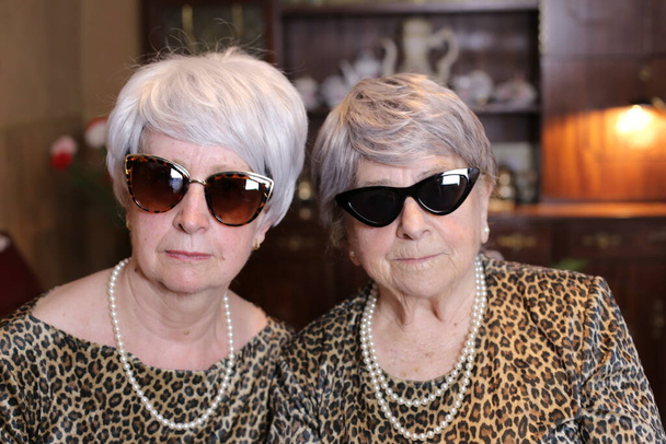 portrét dvou dospělých žen ve stylových šatech s příslušenstvím doma - Fotografie, Obrázek