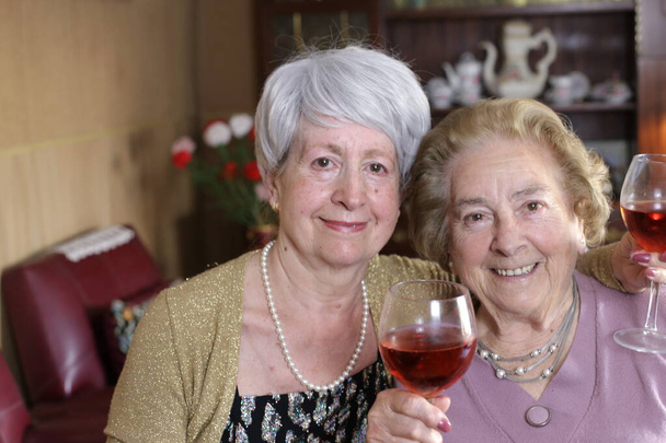 portret dwóch dojrzałych kobiet z czerwonym winem spędzających razem czas w domu - Zdjęcie, obraz