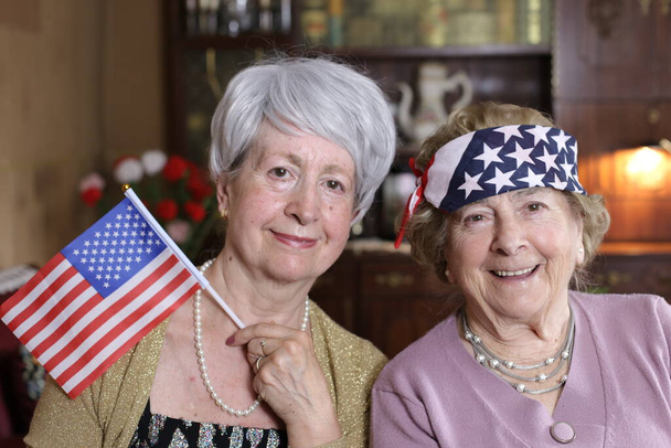 portret van twee volwassen vrouwen met usa vlaggen thuis - Foto, afbeelding