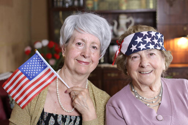 retrato de duas mulheres maduras com bandeiras dos eua em casa - Foto, Imagem