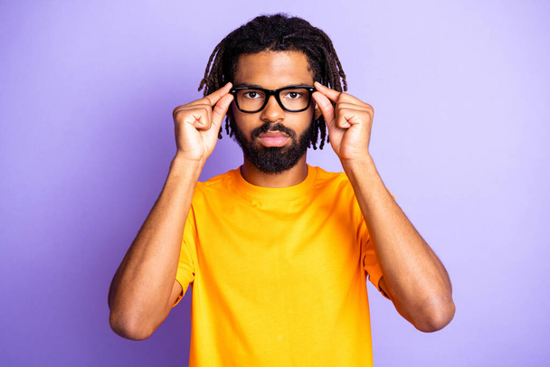 Portrait of nice serious brunette hairdo guy touch spectacles wear orange t-shirt isolated on lilac color background - Photo, Image