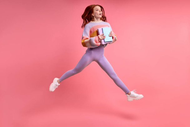 Caucasian cute female student jump high holding notebook in hands, hurry. isolated - Valokuva, kuva