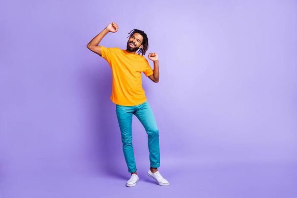 Full size photo of nice optimistic brunette hairdo guy dance wear orange t-shirt pants isolated on lilac color background - 写真・画像