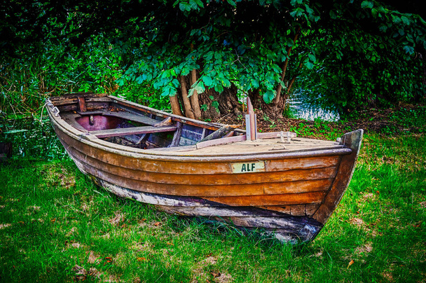 Old wooden rowing boat lying abandoned at the edge of a pond on a meadow. - Photo, Image
