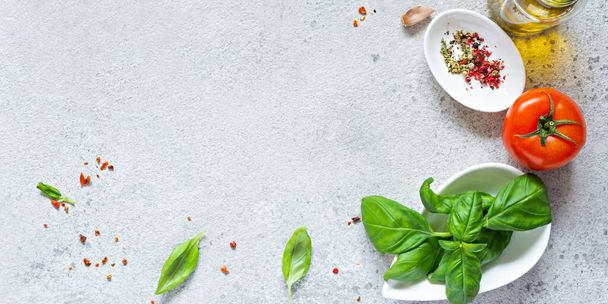 Fresh vegetables and herbs with spices on a gray background. Food background. Flatlay of ripe tomato, fresh basil leaves, garlic and spices, healthy food concept, copy space. - Fotó, kép