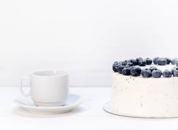 White curd torso with blueberry decoration.next to a white cup and saucer - Fotografie, Obrázek