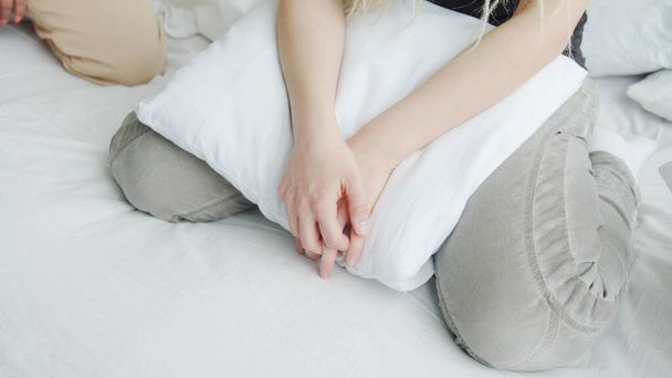 Couple in bed sitting still knee by knee with hands on the pillow - Foto, Bild