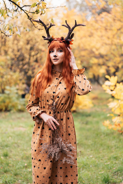 fairy woman with deer horns in autumn forest. Face painting. Beautiful mystery woman. redhead girl with big eyes magical sight - Fotoğraf, Görsel