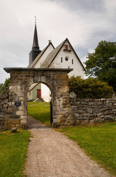 Tingvoll Church, Tingvoll, Norway. The 800 years old Romanesque style church is surrounded by a beautiful stone fence with a beautiful stone archway. - Fotó, kép