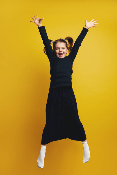Pełne ciało młoda słodka dziewczyna uśmiecha się i podnosząc ręce w górę podczas skoków - Zdjęcie, obraz