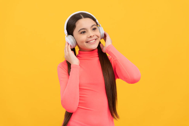 niño feliz escuchar música en auriculares sobre fondo amarillo, música - Foto, Imagen