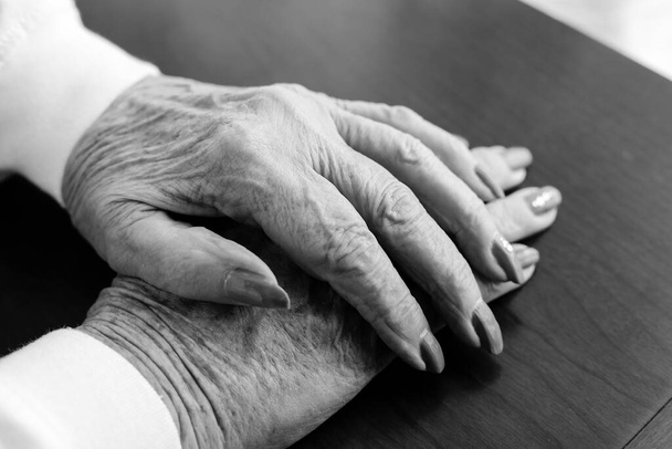 Ein Nahaufnahme-Konzeptfoto eines Paares gerissener und gealterter Hände von einer älteren Frau. - Foto, Bild