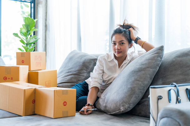 Belle donne asiatiche sedute sul divano con molti pacchi con piccole imprese vendono al cliente sullo shopping online. Concetto di vendita e shopping online da casa - Foto, immagini