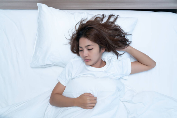 Top uitzicht op mooie jonge vrouw slapen gezellig op een bed in zijn slaapkamer 's nachts. - Foto, afbeelding