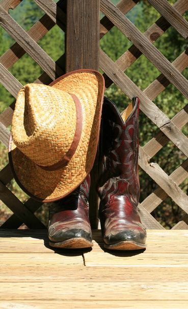 Botas de cowboy. Western Wear. Cowboy Boots, Cowboy Hat e Six Shooter Pistol. Um par de botas ocidentais de couro vermelho com um chapéu de palha dourado. Imagem ocidental rústica de botas de cowboy, chapéu de cowboy e arma. botas de cowboy decorativas. Botas de cowboy e chapéu. - Foto, Imagem