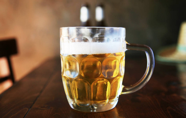 ビールだ。ビールのグラスマグカップ。レストランでビール。ビールのグラス。オクトーバーフェストビール。厚い泡の頭を持つ黄金のラガーでいっぱいのガラスビールマグカップ。オクトーバーフェスト。ビヤマグ。バイエルンとミュンヘンオクトーバーフェストからのラガービールの大きなガラス。祭りと醸造所.  - 写真・画像
