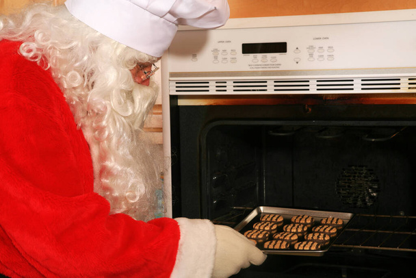 Le Père Noël fait des biscuits. Biscuits de Noël. Le Père Noël fait cuire des biscuits de Noël de l'intérieur de son four. Biscuits au four frais. Santa cuisson pour Noël. Cookies de vacances d'hiver. À l'intérieur d'un four à biscuits. C'est l'heure des cookies. Ho Ho Ho - Photo, image