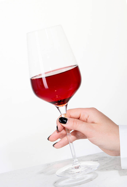 Young woman holding glass of rose wine on white background. Hand with black polish. - Foto, imagen