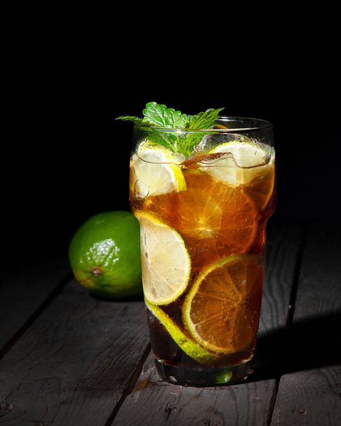 Fresh made longdrink Cuba libre cocktail on dark background. Front view, Copy space - Фото, изображение