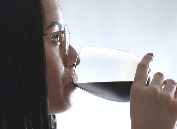 A Hispanic female drinking wine isolated on a white background - Foto, Bild