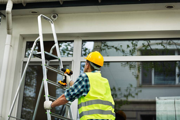 Worker install camera on outdoors CCTV Installation Wizard concept. Service for installing CCTV cameras. - Fotoğraf, Görsel