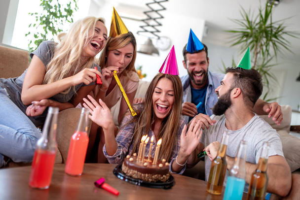 Ομάδα χαρούμενων νέων φίλων που κάνουν πάρτι γενεθλίων στο σπίτι. - Φωτογραφία, εικόνα