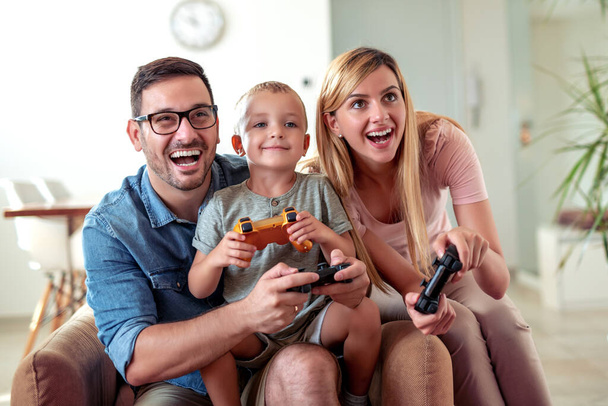 Onnellinen perhe pelaa videopelejä kotona ja pitää hauskaa yhdessä. - Valokuva, kuva