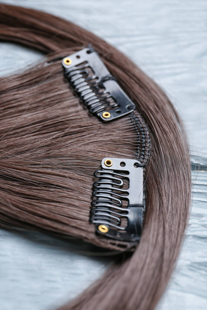 Sznurek brunetka włosy na kolorowym drewnianym tle, zbliżenie - Zdjęcie, obraz
