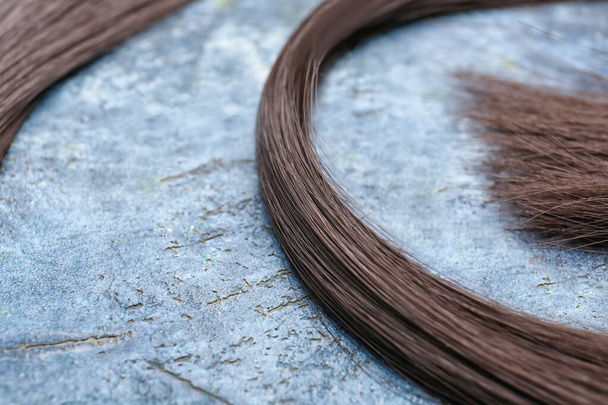 Strang brünettes Haar auf Grunge-Hintergrund, Nahaufnahme - Foto, Bild