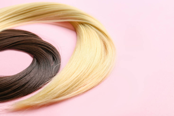 Brins de cheveux bruns et blonds sur fond de couleur, gros plan - Photo, image
