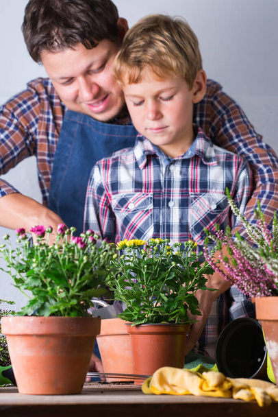 El niño ayuda al padre a plantar flores. Tiempo en familia en casa - Foto, imagen