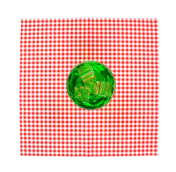Верхний вид стекла с зеленой водой на красной скатерти - Фото, изображение