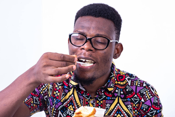 portret van knappe jongeman ontbijten tijdens het drinken van yoghurt met croissant. - Foto, afbeelding