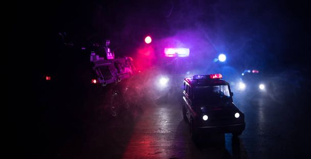 Carros da polícia à noite. Carro da polícia perseguindo um carro à noite com fundo de nevoeiro. 911 Resposta de emergência carro da polícia acelerando para o local do crime. Foco seletivo - Foto, Imagem