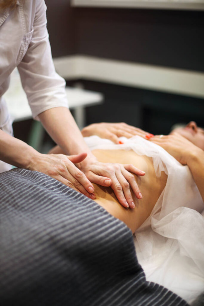 Teilweise Ansicht von Masseur Magen-Massage für weibliche auf Massagetisch - Foto, Bild