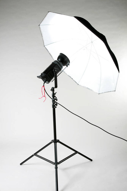 Στούντιο Λάιτς. Εξοπλισμός φωτισμού στούντιο. λευκό φωτισμό ομπρέλας. Λευκό μαλακό κουτί. Φωτιστικά στούντιο. Απομονωμένο σε λευκό. Υπάρχει χώρος για μήνυμα. ένα μόνο στούντιο flash σε ένα τρίποδο. Το Studio Flash χρησιμοποιείται στη φωτογραφία. επαγγελματικό φωτογραφικό εξοπλισμό. φώτα.  - Φωτογραφία, εικόνα