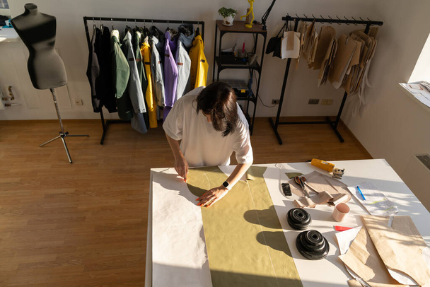Schneiden von Textilien aus Papiermuster. Entwurf eines Modedesigners über Stoffarbeiten im Atelier, Draufsicht - Foto, Bild