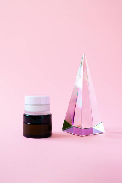 Set moisturizer cream jars and glass pyramid prism on pink background with copy space, vertical. Beauty skin care cosmetic products trendy minimalism - Photo, Image