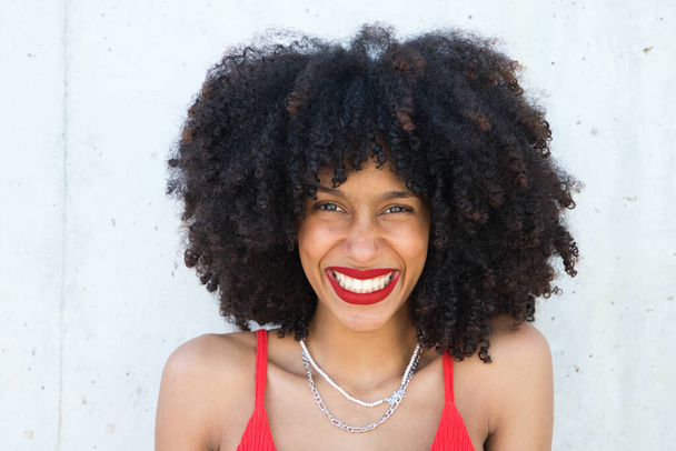 piękna afro amerykańska kobieta uśmiecha się i patrząc w aparat robi różne pozy i gesty z jej twarzy. Kobieta ma czerwoną bluzkę i czerwoną szminkę. Pojęcie szczęścia - Zdjęcie, obraz