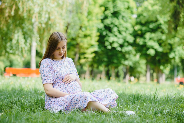 Beautiful pregnant woman relaxing in the park - Photo, image