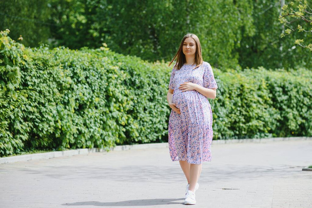 Beautiful pregnant woman relaxing in the park - Фото, изображение