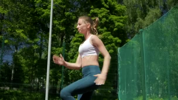 Kaukasische sportieve blonde rondborstige mooie vrouwelijke vlek lopen, sprinten op zijn plaats - Video