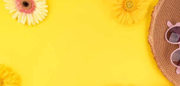 Жовтий модний святковий фон з солом'яним капелюхом, сонцезахисними окулярами, рожевими квітами гербери на монохромі
 - Фото, зображення